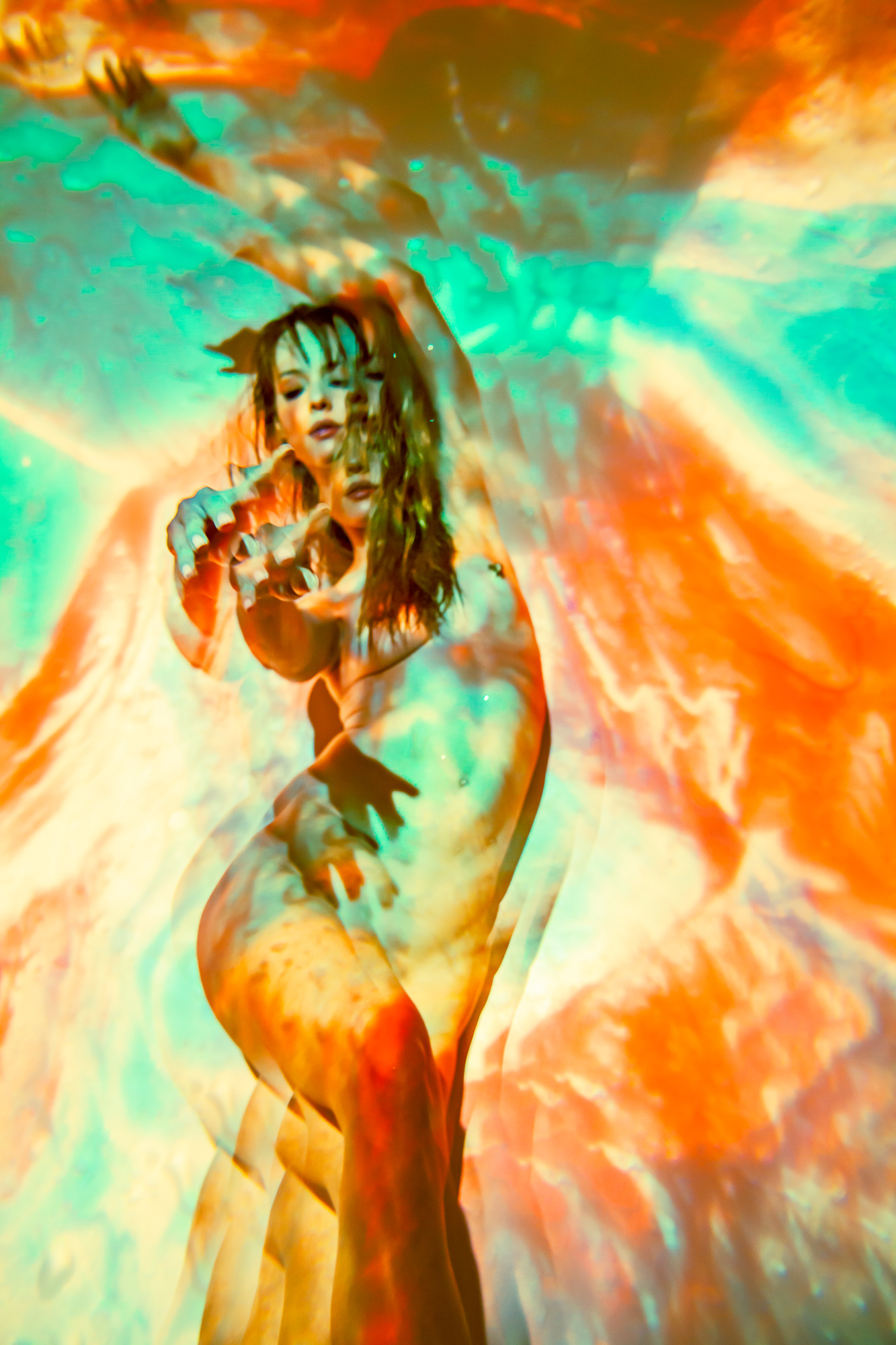 An outstretched hand and standing figure refracted through orange and turquoise projected light